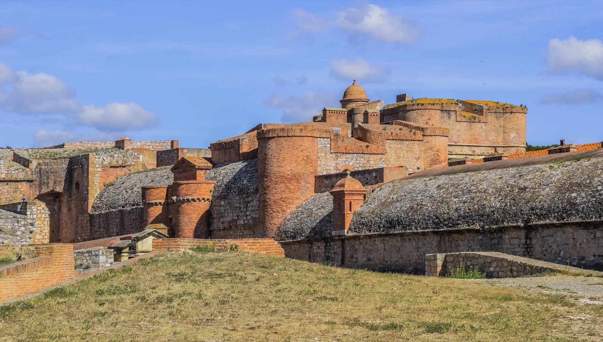 Les remparts de briques roses de la forteresse de Salses sous un ciel bleu