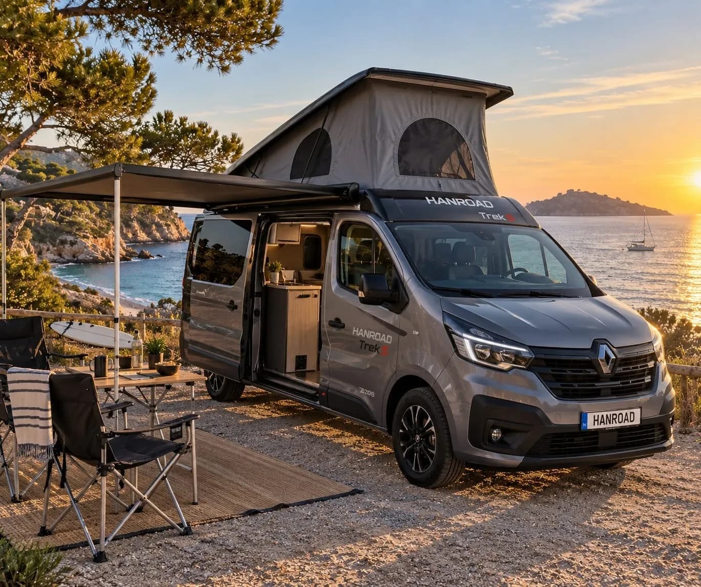 Le Hanroad Trek gris, toit relevé et store déplié, garé face à la mer au coucher du soleil, table et chaises installées à côté